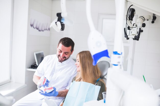 Il dentista maschio felice che mostra i denti modella al paziente