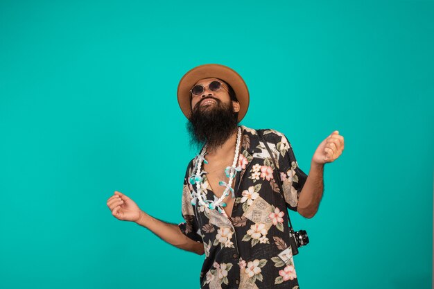 Il di un uomo felice con una lunga barba che indossa un cappello, indossa una camicia a righe che mostra un gesto su un blu.