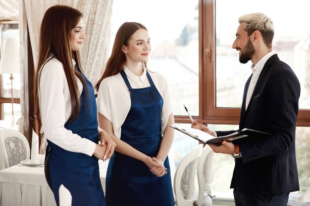 Il direttore del ristorante bello sta parlando con le cameriere del processo di lavoro