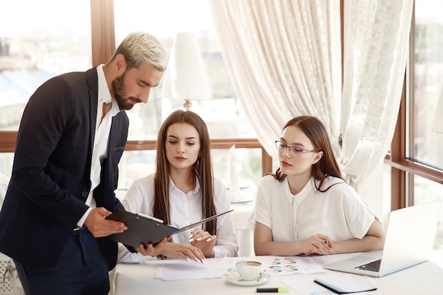 Il direttore del ristorante sta mostrando schemi finanziari nei documenti e due assistenti che le donne ascoltano con attenzione