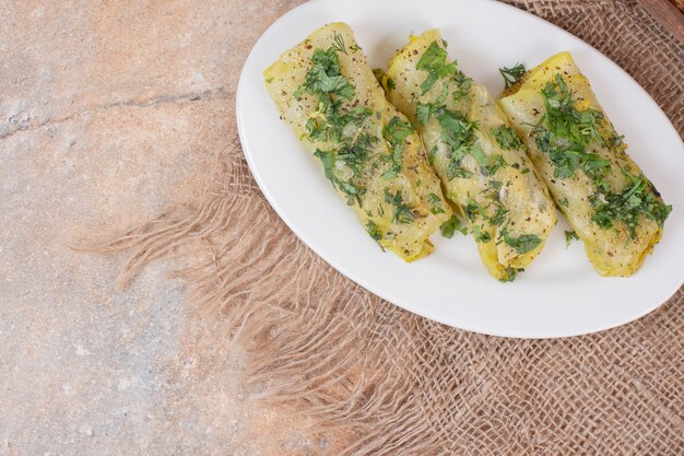 Il dolma del cavolo rotola sulla zolla bianca decorata con le erbe.