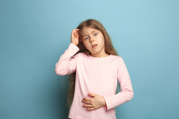 Il dolore addominale. Ragazza teenager su un blu. Le espressioni facciali e le emozioni delle persone concetto