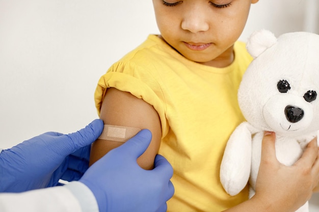 Il dottore attacca un cerotto sulla spalla di una ragazza dopo la vaccinazione