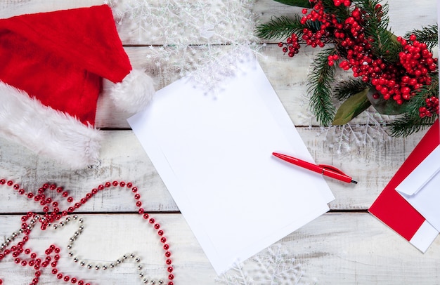 Il foglio di carta bianco sul tavolo di legno con una penna e decorazioni natalizie.