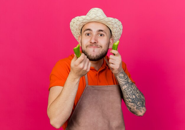 Il giardiniere maschio allegro che porta il cappello di giardinaggio tiene lo sguardo rotto del pepe