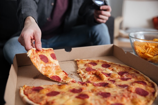 Il giocatore del giovane gioca con il joystick mentre mangia.