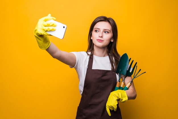 Il giovane ardener womang prende selfie sul telefono mentre tiene gli strumenti isolati