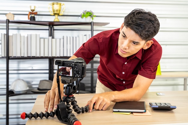 Il giovane blogger asiatico di sesso maschile prepara e imposta la fotocamera per video dal vivo e recensioni per vendere prodotti Social media e concetto di influencer online