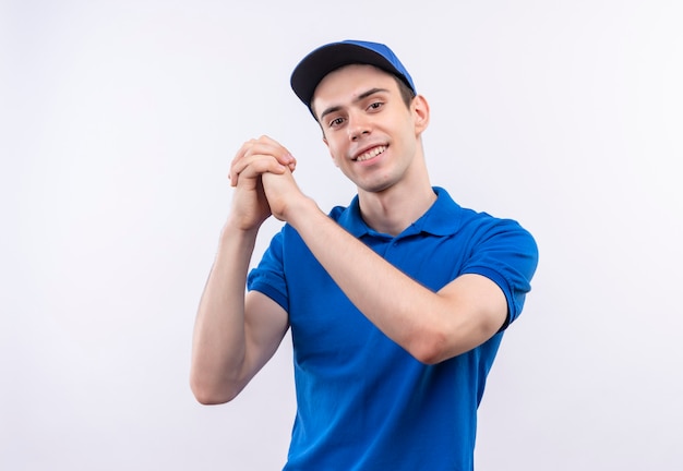 Il giovane corriere che indossa l'uniforme blu e il berretto blu sorride e ringrazia