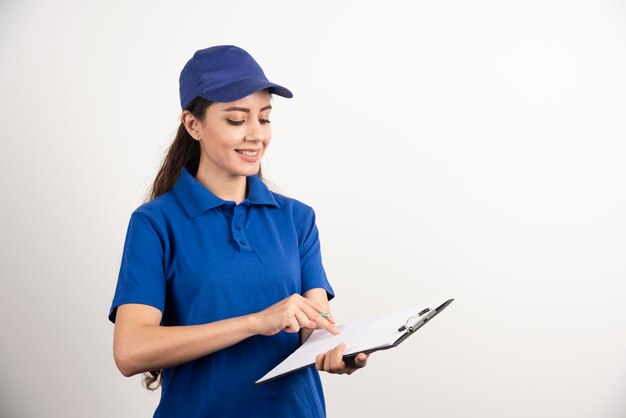 Il giovane corriere femminile in blu frega che tiene una lavagna per appunti. Foto di alta qualità