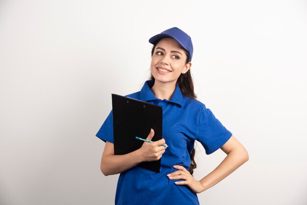 Il giovane corriere femminile in blu frega che tiene una lavagna per appunti. Foto di alta qualità