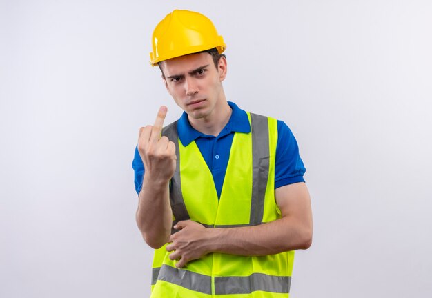 Il giovane costruttore indossa l'uniforme da costruzione e il casco di sicurezza mostra cazzo arrabbiato