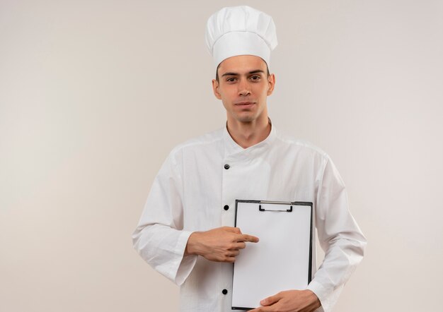 Il giovane cuoco maschio soddisfatto che indossa l'uniforme dello chef punta il dito negli appunti in mano con lo spazio della copia