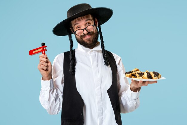 Il giovane ebreo ortodosso con biscotti hamantaschen per il festival Purim. Vacanza, celebrazione, giudaismo, pasticceria, tradizione, biscotto, concetto di religione
