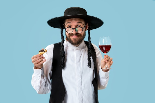 Il giovane ebreo ortodosso con cappello nero con biscotti Hamantaschen per la festa ebraica di Purim