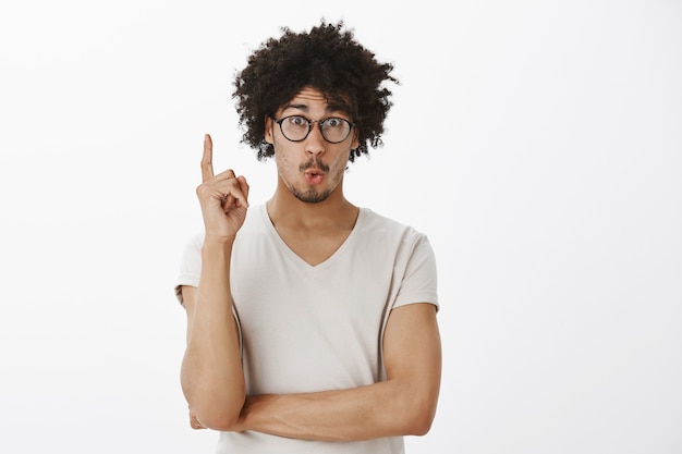 Il giovane eccitato, lo studente ha un'idea, alzando il dito e sorridendo felice