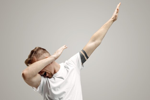 Il giovane fa un movimento di tocco con le braccia su uno spazio grigio