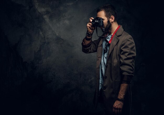 Il giovane fotografo concentrato sta scattando una foto sullo sfondo scuro del grunge.