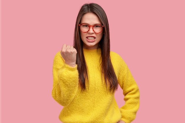 Il giovane irritabile mostra il pugno con rabbia, stringe i denti, combatte contro l'ingiustizia e la violenza, vestito con abiti casual