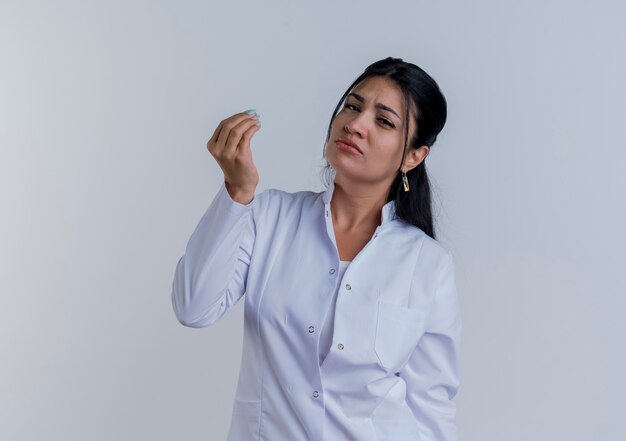 Il giovane medico femminile dispiaciuto che porta la veste medica che osserva tenendo la mano nell'aria finge che tiene qualcosa di isolato