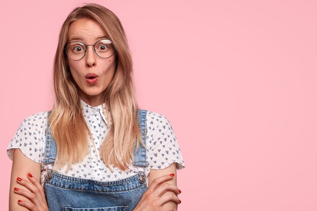 Il giovane modello femminile stupito guarda con espressione sbalordita alla macchina fotografica