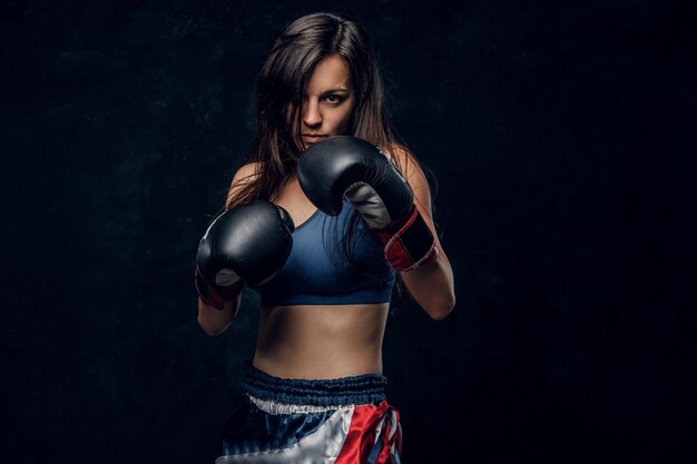 Il giovane pugile femminile attraente con capelli lunghi e guantoni da boxe è pronto a combattere.