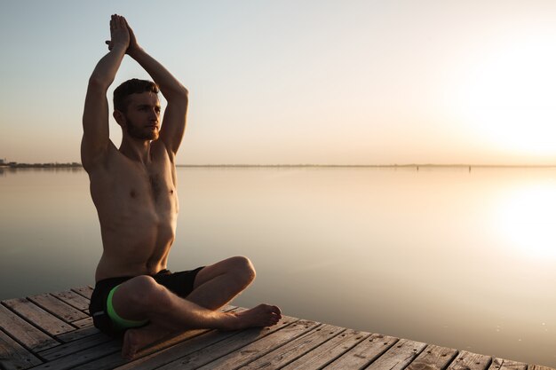 Il giovane sportivo concentrato fa gli esercizi di meditazione di yoga