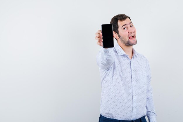 Il giovane sta mostrando un'idea di mockup con il telefono cellulare su sfondo bianco