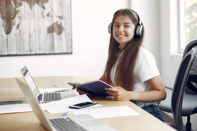 Il giovane studente che si siede alla tavola e usa il computer portatile