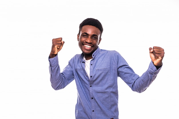 Il giovane uomo africano con le mani sollevate celebra la vittoria isolata sulla parete bianca