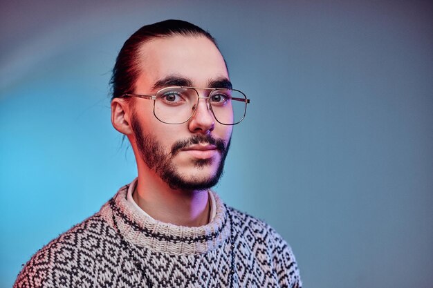 Il giovane uomo attraente con gli occhiali sta posando per il fotografo in studio.