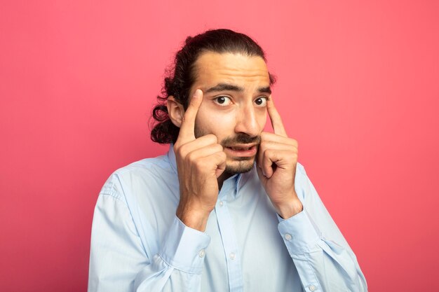 Il giovane uomo caucasico bello che fa pensa il gesto isolato sulla parete cremisi