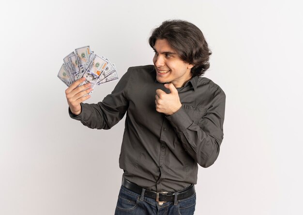 Il giovane uomo caucasico bello gioioso tiene ed esamina i soldi isolati su fondo bianco con lo spazio della copia
