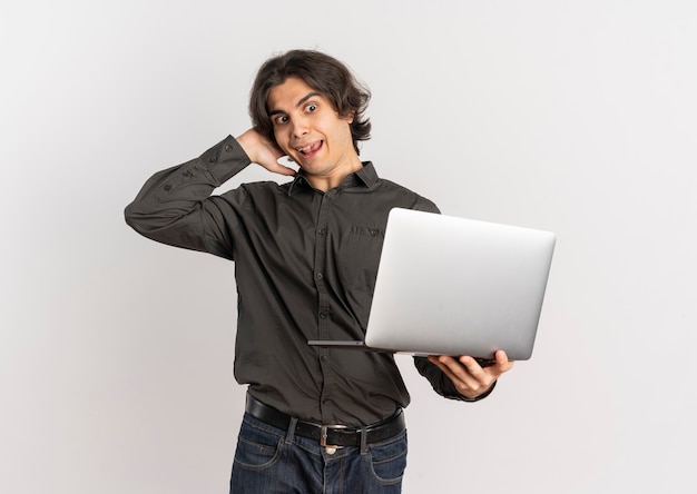 Il giovane uomo caucasico bello sorpreso tiene la testa behinf e guarda il laptop isolato su priorità bassa bianca con lo spazio della copia
