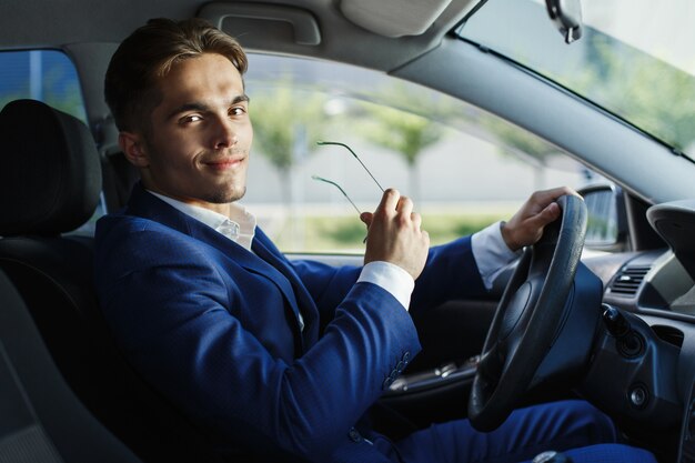 Il giovane uomo d&#39;affari bello si siede al volante dentro l&#39;automobile