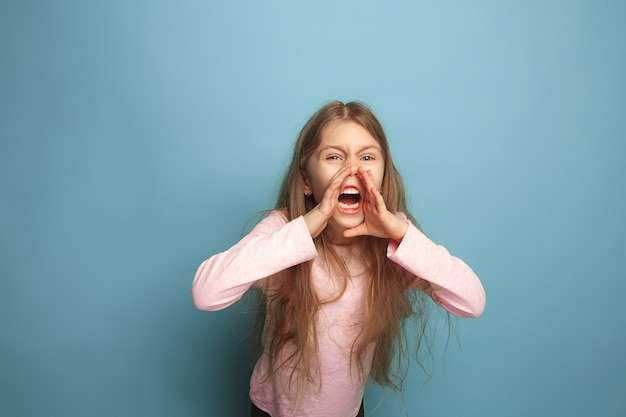 Il grido. Ragazza teenager su un blu. Le espressioni facciali e le emozioni delle persone concetto