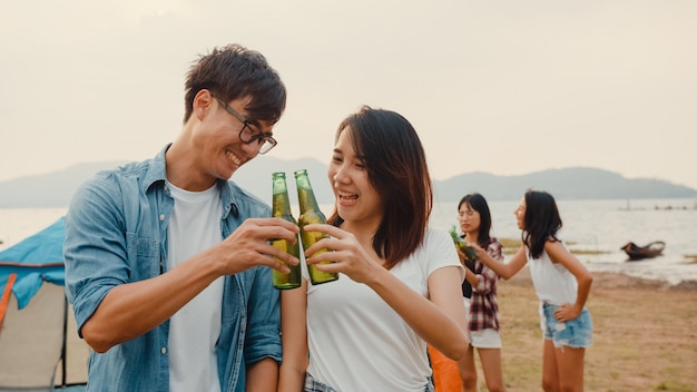 Il gruppo di adolescenti asiatici migliori amici si concentra su una coppia di brindisi con birra e gode di una festa in campeggio con momenti felici insieme accanto alle tende nel parco nazionale