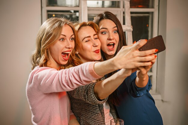 Il gruppo di amici che godono della sera beve con la birra e le ragazze che fanno la foto del selfie