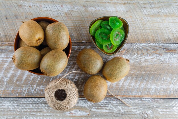 Il kiwi in una ciotola con le fette secche, filo piatto appoggia su un tavolo di legno