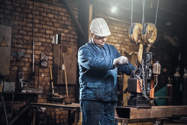 Il lavoratore concentrato sta usando un piccolo trapano mobile per praticare dei fori nella parte della rotaia.