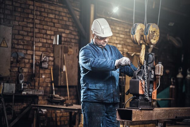 Il lavoratore concentrato sta usando un piccolo trapano mobile per praticare dei fori nella parte della rotaia.