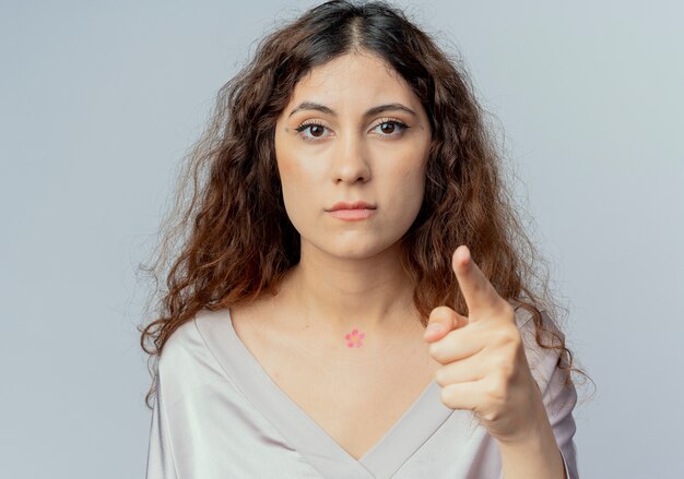 Il lavoratore di ufficio femminile abbastanza giovane rigoroso indica alla macchina fotografica isolata su bianco