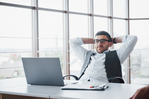 Il lavoratore è un giovane con un computer portatile in ufficio