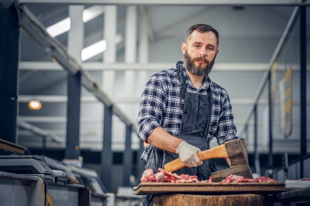 Il macellaio barbuto vestito con una camicia di pile taglia carne fresca.