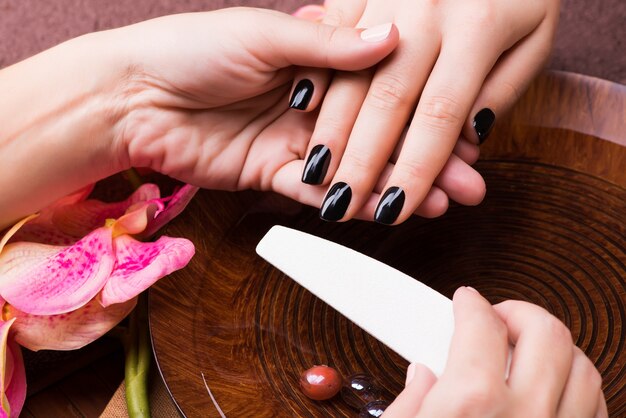 Il maestro del manicure fa la manicure sulle mani della donna - concetto di trattamento termale