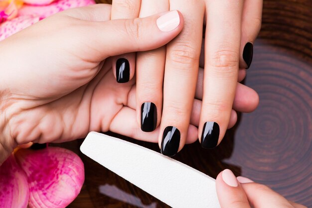 Il maestro del manicure fa la manicure sulle mani della donna - concetto di trattamento termale