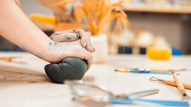 Il maestro di scolpire la ceramica lavora in uno studio impastando un pezzo di argilla con le mani