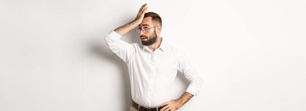 Il manager dell'uomo infastidito alza gli occhi al cielo e schiaffeggia la fronte con il palmo della mano da qualcosa di noioso in piedi sopra w