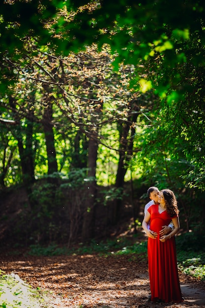 Il marito con la moglie incinta che abbraccia nella foresta