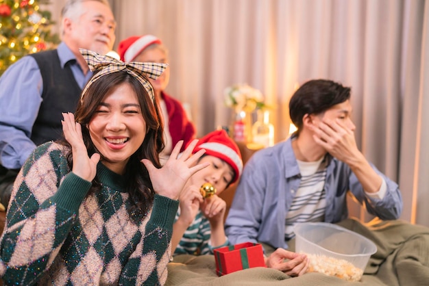 Il maschio adulto asiatico dà la scatola regalo al genitore durante le vacanze di Natale mentre utilizza lo smartphone parlando selfie foto felicità insieme in soggiorno sul divano divano relazione familiare legame interno di casa